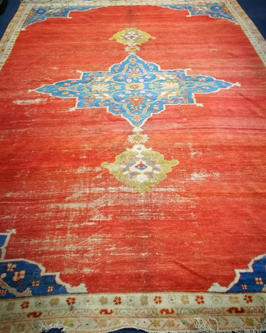 A Persian red ground carpet, worn 415 x 300cm.